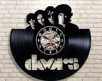 Könnte beinhalten: Schwarze Vinyl-Schallplattenuhr mit einer Silhouette der Bandmitglieder von The Doors. Das Zifferblatt hat ein sichtbares mechanisches Uhrwerk und weiße Ziffern. Der Name der Band, "doors", ist am unteren Rand der Schallplatte ausgeschnitten.