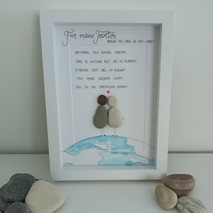 May include: A framed piece of art with a watercolour background and two figures made of stones. The text in the image reads "For my daughter, never forget that I love you! Remember always that you are braver than you believe, stronger than you believe, and more loved than you can imagine."