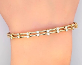 May include: A gold bangle bracelet with a double row of small, clear diamonds.