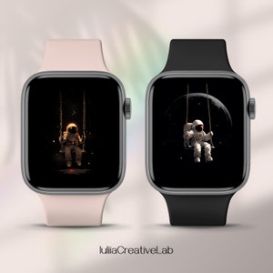 May include: Two Apple Watch Series 7 smartwatches with black watch faces displaying an astronaut on a swing in space. The watch on the left has a pink band and the watch on the right has a black band.