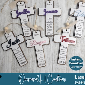 May include: Ten wooden cross shapes with various colours and designs. Each cross has a name and a bible verse. The crosses are arranged on a white surface.