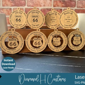 Puede incluir: Adornos de madera cortados con láser de la Ruta 66. Cada adorno presenta el logotipo del escudo de la Ruta 66, los años 1926-2026 y la distancia de 3.940 km. También se incluyen los nombres de las ciudades a lo largo de la ruta. Las palabras "Descarga instantánea Laser Ready" son visibles.