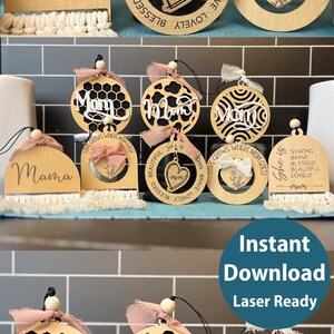May include: A set of laser-cut wooden ornaments with different designs featuring the word "Mom". The ornaments are decorated with a variety of patterns, including honeycomb, hearts, and swirls. The ornaments are laser-ready and come with SVG, PNG, PDF, and AI files.