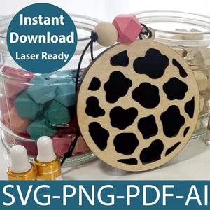May include: A wooden cutout of a cow print design with black and white spots. The cutout is hanging from a string with a pink and white bead. The text "Instant Download Laser Ready" is visible in the image.