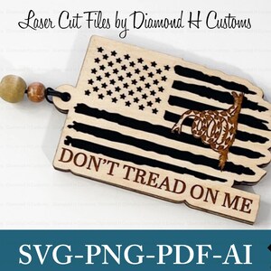 May include: A wooden cutout of an American flag with a rattlesnake and the text "DON'T TREAD ON ME". The cutout is laser cut and is available in SVG, PNG, PDF, and AI formats.