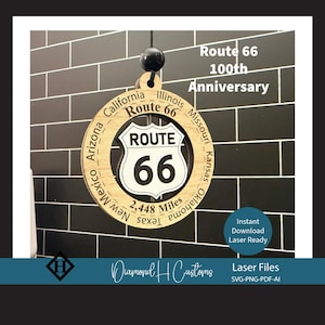 May include: A wooden Route 66 sign commemorating the 100th anniversary. The sign features the iconic Route 66 shield with the text "Route 66" and "66". The sign also includes the names of states along the route and the text "2,448 Miles".