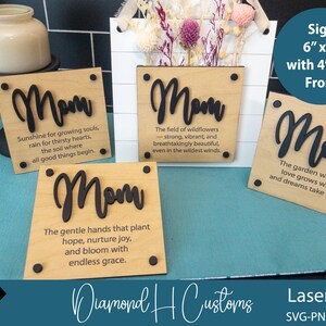 May include: Four wooden signs with the word "Mom" in black lettering and inspirational quotes about mothers. The signs are 6 inches by 6 inches with a 4 inch by 4 inch front. The signs are on a blue surface.