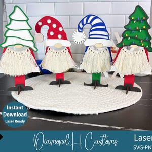 Pode incluir: Quatro decorações de gnomos de madeira com diferentes designs de chapéus: uma árvore de Natal branca, um chapéu vermelho de bolinhas, um chapéu listrado azul e branco e uma árvore de Natal verde com luzes. Cada gnomo tem uma barba branca.