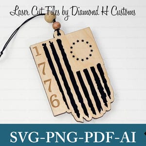 May include: A wooden ornament featuring a distressed American flag design with 13 stars in a circle and the number 1776. The ornament is attached to a brown cord.