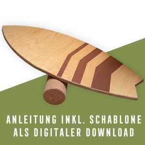 Puede incluir: Una tabla de equilibrio de madera con forma de tabla de surf, con rayas de chevron marrones. Descansa sobre un rodillo cilíndrico de corcho. El texto en el fondo verde dice: "ANLEITUNG INKL. SCHABLONE ALS DIGITALER DOWNLOAD."