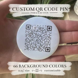 May include: A white pinback button with a QR code design. The button is 2.25 inches in size and customizable with 66 background colors. Text at the top reads "CUSTOM QR CODE PIN" and "PINBACK BUTTON".