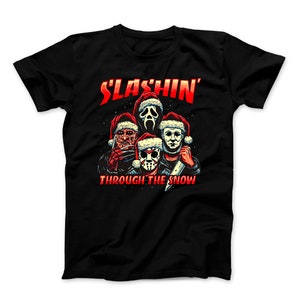 May include: Black t-shirt with a graphic of four horror movie characters wearing Santa hats and holding weapons. The text "SLASHIN' THROUGH THE SNOW" is printed below the characters.