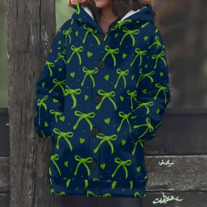 Peut inclure: Veste à capuche bleu marine ornée de motifs de nœuds vert lime et de petits cœurs verts. La veste est dotée d'une fermeture boutonnée sur le devant et d'une doublure intérieure blanche. Fabriquée dans une matière douce et confortable.