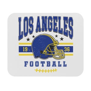 May include: White square coaster with a distressed design featuring the text "LOS ANGELES" in blue, a blue football helmet, and the word "FOOTBALL". The design includes yellow stripes, stars, and the numbers "19" and "36".