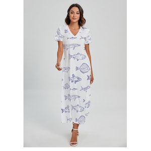 Puede incluir: Vestido largo blanco con cuello en V y mangas cortas. El vestido presenta un patrón repetido de ilustraciones de peces azules. La modelo lleva sandalias blancas. El vestido es de estilo casual y veraniego.