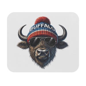 May include: A square coaster featuring a detailed illustration of a bison wearing a red, white, and blue striped beanie with the word "BUFFALO" and aviator sunglasses. The bison has large curved horns and a shaggy coat.