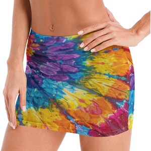 May include: A mini skirt with a vibrant tie-dye pattern. The skirt features a swirling design of colors including blue, purple, yellow, orange, and red. The fabric appears to be soft and form-fitting.