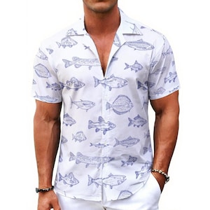 Puede incluir: Camisa blanca de manga corta con estampado de peces azules. La camisa, con cuello de campamento, presenta ilustraciones de varios peces. La tela es ligera.