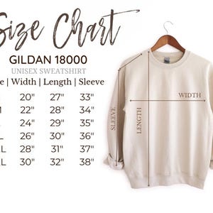 K&ouml;nnte beinhalten: Beiges Gildan 18000 Unisex-Sweatshirt an einem Holzb&uuml;gel. Das Bild enth&auml;lt eine Gr&ouml;&szlig;entabelle mit Ma&szlig;en in cm f&uuml;r Breite, L&auml;nge und &Auml;rmell&auml;nge, von Gr&ouml;&szlig;e S bis 3XL.
