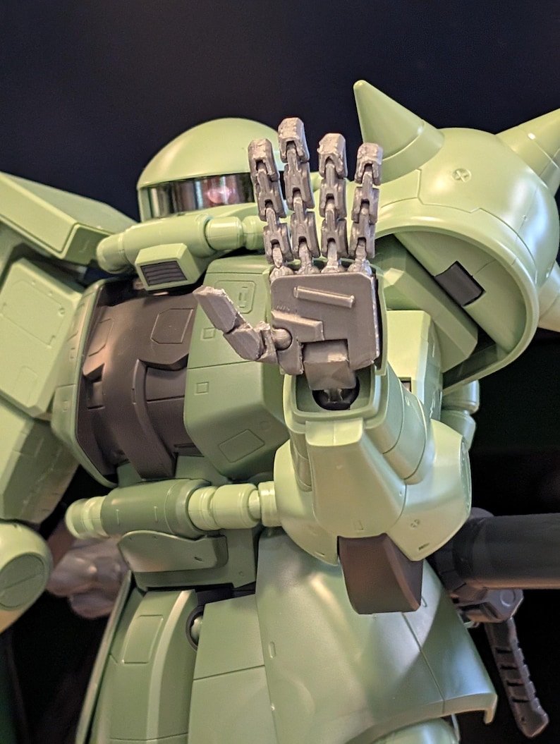 Op de afbeelding: Gedetailleerde afbeelding van een lichtgroene robot met gearticuleerde handen die een stopgebaar maken. De robot heeft een afgeronde kop, een hoekig lichaam en diverse mechanische details. De hand is zilver.