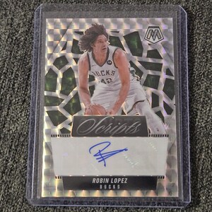 May include: A basketball trading card featuring Robin Lopez of the Bucks. The card has a mosaic background and a signature. The player is wearing a white and green jersey. The word "Scripts" is written on the card.