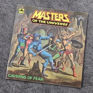 May include: Vintage "Masters of the Universe" Golden book cover. The cover depicts action figures in a cave setting. The title is in yellow and red, with the text "Caverns of Fear" at the bottom.
