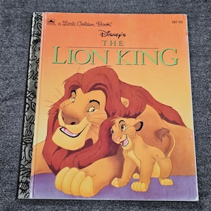 May include: A Little Golden Book titled "Disney's The Lion King." The cover features a smiling lion with a red mane and a smaller lion cub. The background is orange and purple.