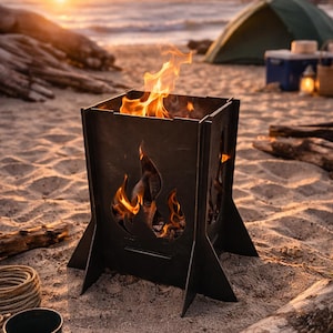 Può includere: Un braciere in metallo nero con intagli a forma di fiamma, che brucia brillantemente su una spiaggia sabbiosa. Il braciere è quadrato con gambe angolate. Una tenda verde e il mare sullo sfondo.