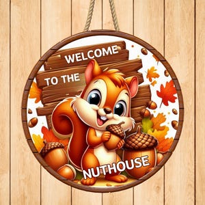May include: Round wooden sign with a cartoon squirrel holding an acorn. The sign reads "Welcome to the Nuthouse" with fall leaves and acorns. The sign is brown with a rope for hanging.