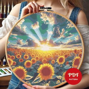 Może przedstawiać: Wzór na haft krzyżykowy przedstawiający pole słoneczników z jasnym zachodem słońca w tle. Wzór znajduje się w drewnianej obręczy do haftu, a w prawym dolnym rogu widoczny jest tekst "PDF PATTERN".