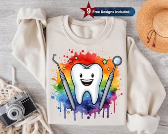 May include: A white sweatshirt with a colorful watercolor design of a cartoon tooth with a happy face, a dental mirror, and a dental pick. The design includes rainbow colors and stars. The text "9 Free Designs Included" is in a red star.