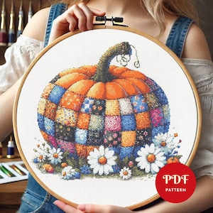 May include: A cross-stitch pattern featuring a colourful patchwork pumpkin with a brown stem and white daisies. The pattern is in a wooden embroidery hoop and the text "PDF PATTERN" is in the lower right corner.
