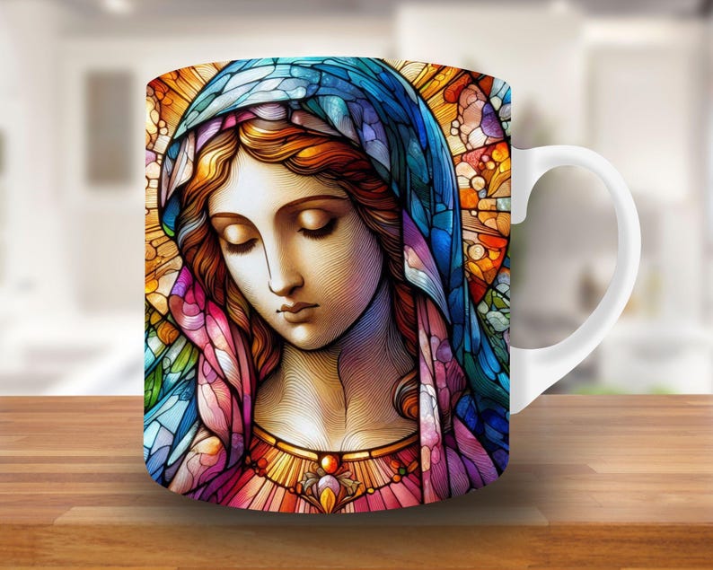 May include: A white ceramic mug with a stained glass design of a woman with a blue and purple robe. The woman's face is detailed with brown eyes and a soft smile.