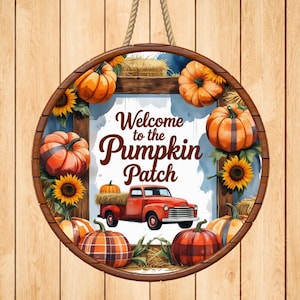 Puede incluir: Cartel de madera redondo con una cuerda para colgar, con temática otoñal. El cartel dice "Welcome to the Pumpkin Patch" e incluye calabazas, girasoles y una camioneta roja. El cartel está enmarcado en madera.
