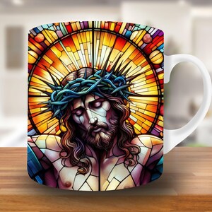May include: White ceramic mug with a stained glass design featuring a depiction of Jesus Christ with a crown of thorns. The stained glass design is in shades of red, orange, yellow, blue, and purple.