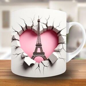 May include: White ceramic mug with a design of the Eiffel Tower breaking through a cracked wall with a pink heart behind it.