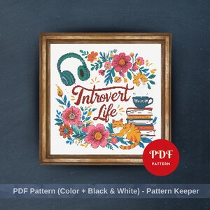 May include: Cross-stitch pattern in a wooden frame. The design features the text "Introvert Life" surrounded by flowers, a cat, headphones, a stack of books, and a teacup. A red circle with "PDF Pattern" is in the bottom right.