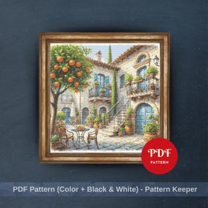 May include: A framed cross-stitch pattern depicts a Mediterranean courtyard scene. The artwork features a tree with orange fruit, blue doors, and potted plants. The frame is a warm, light brown color, and the text "PDF PATTERN" is visible.