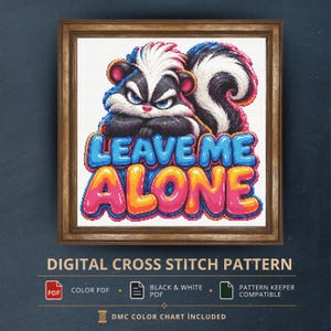 Può includere: Uno schema a punto croce raffigurante una puzzola dal pelo bianco e nero, posizionata sopra il testo LEAVE ME ALONE in lettere a bolla blu e rosa. Il disegno è incorniciato da un bordo in legno con icone di file digitali sottostanti.