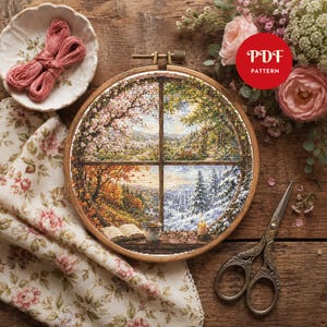 Puede incluir: Un bastidor de bordado circular de madera que contiene un patrón de punto de cruz que representa las cuatro estaciones a través de un marco de ventana. El diseño muestra paisajes de primavera, verano, otoño e invierno. Se ve un icono rojo PDF PATTERN.