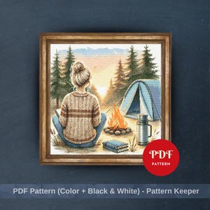 May include: Cross-stitch pattern of a person sitting by a campfire in a forest, with a tent and trees in the background. The image is framed and includes the text "PDF Pattern (Color + Black & White) - Pattern Keeper".
