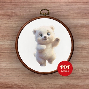 May include: A cross-stitch pattern of a white polar bear waving, set in a wooden embroidery hoop. The bear has blue eyes and is smiling. A red circle with the text "PDF PATTERN" is in the lower right corner.