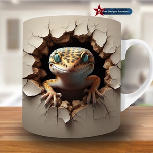 May include: White ceramic mug with a 3D printed design of a gecko lizard peeking out of a cracked wall. The gecko has a yellow and brown patterned body with blue eyes.