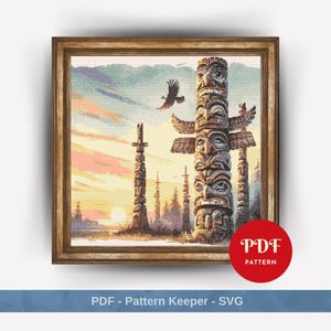 May include: A cross-stitch pattern depicting a colourful sunset scene with three totem poles in front of a forest. The totem poles are carved with intricate designs and faces. The pattern is framed in a brown wooden frame.