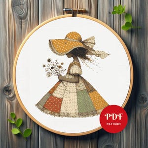 Peut inclure: Patron de point de croix représentant une fille portant un chapeau jaune à pois blancs et une robe en patchwork tenant un bouquet de fleurs. Le motif est intitulé "PDF PATTERN".