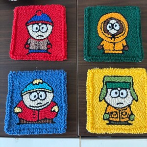 Pode incluir: Quatro bases para copos quadradas, feitas à mão, com personagens da série animada. Cada base para copos tem um personagem diferente em um fundo de cor diferente: vermelho, verde, azul e amarelo. Os personagens são retratados com olhos grandes e roupas simples.
