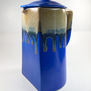 May include: A blue ceramic pitcher with a lid. The pitcher has a drip glaze design in brown and blue.