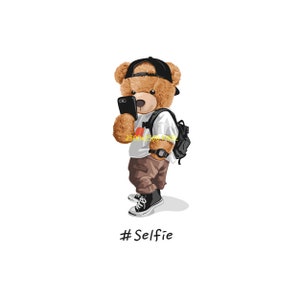 May include: A brown teddy bear wearing a black baseball cap, white shirt, brown pants, and black sneakers. The bear is holding a black smartphone and taking a selfie. The text #Selfie is written below the bear.