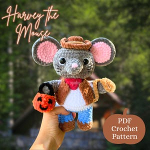 May include: A handmade crochet mouse named "Harvey" wearing a cowboy hat, vest, and blue jeans, holding an orange pumpkin-shaped bag. The mouse has gray fur, pink ears, and a red bandana. Text on the image reads "Harvey the Mouse" and "PDF Crochet Pattern."