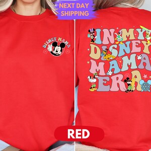 May include: Red sweatshirt with a Mickey Mouse graphic on the front and the text "In My Disney Mama Era" with various Disney characters on the back.